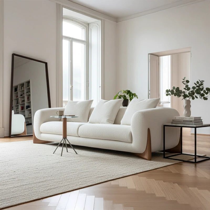 Modern living room with a white sofa, round marble coffee table, and decorative elements.
