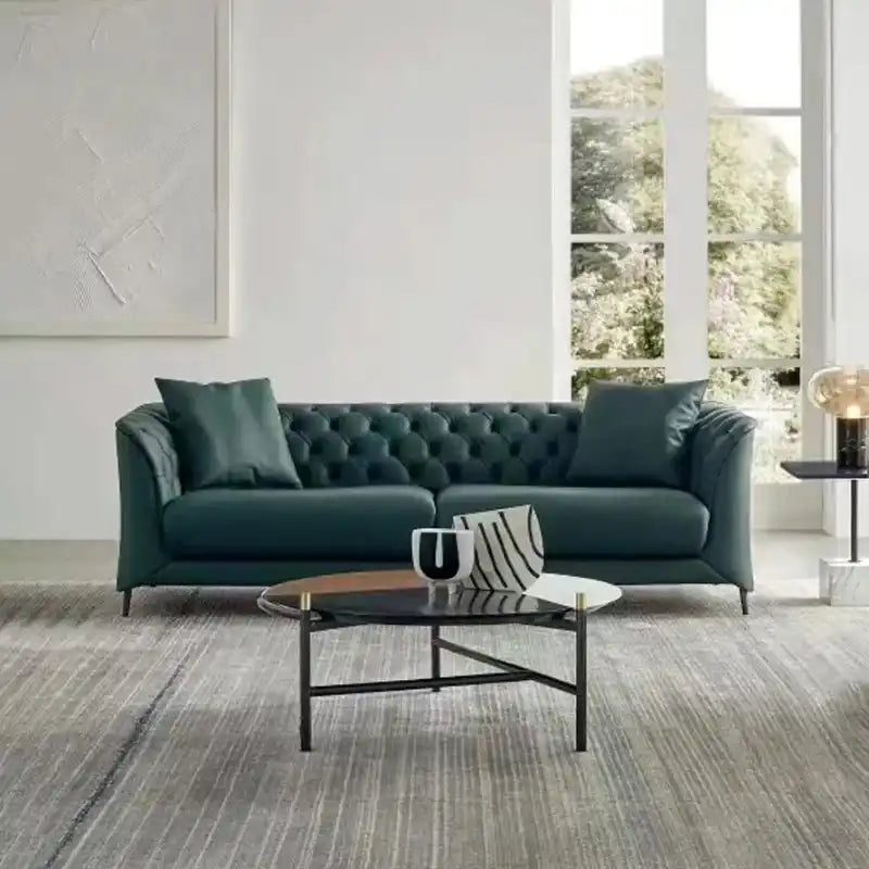 classic dark faux leather sofa with deep button details, high back and broad supportive arms — front view in a bright livi...