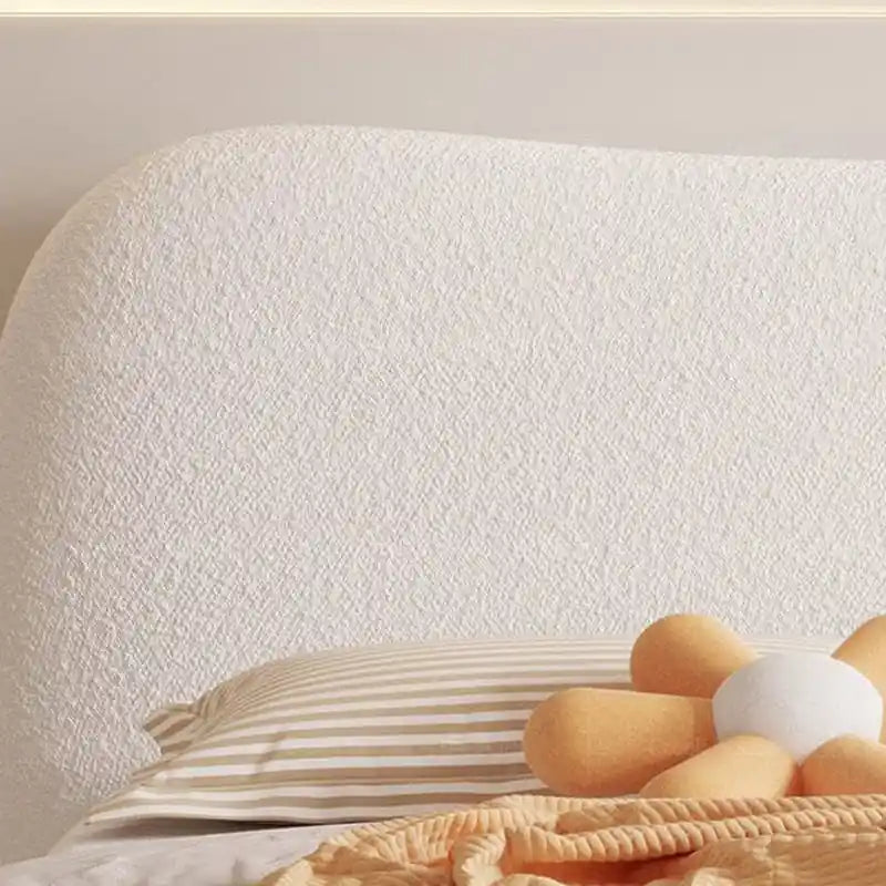 The soft off-white bouclé fabric, curved padded headboard, and neatly rounded base offer a minimalist appeal