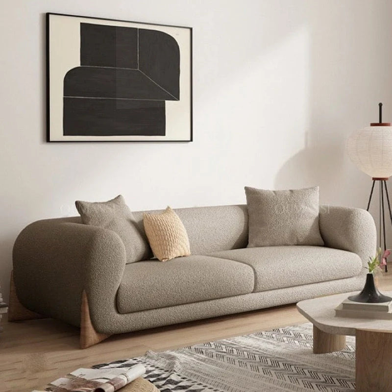 Upholstered in textured bouclé fabric in shades like taupe or ivory, the Boston settee features rounded curves, deep seating, and organically integrated arms for a warm and inviting feel. 